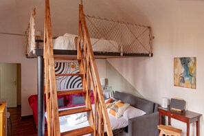 A room with a bunk bed, a desk, a chair, a sofa, and a painting on the wall.