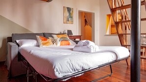 A bedroom with a bed, pillows, a painting, and a wooden staircase. - 'Borghetto House - Pisa' Apartment with Private Terrace and Wi-Fi (Pisa)