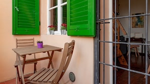 An outdoor wooden table and chairs, a window with green shutters, and a metal gate. - 'Borghetto House - Pisa' Apartment with Private Terrace and Wi-Fi (Pisa)