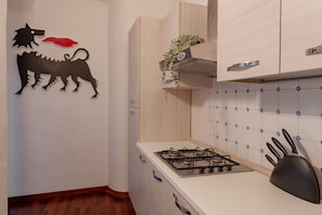 A kitchen with a gas stove, cabinets, and a wall decoration.