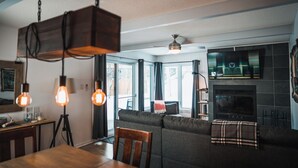 A modern living room with a sofa, dining table, and hanging light fixtures.
