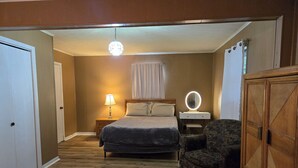 A bedroom with a bed, bedside table, lamp, vanity mirror, and a chair. - A+ location: UT, Melton Hill Parks, ORNL, shops (Oak Ridge)