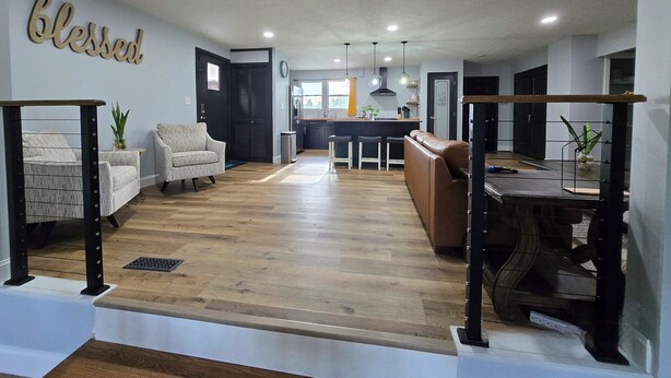 A spacious living area with a wooden floor, a sofa, a dining table, and a kitchen in the background. - A+ location: UT, Melton Hill Parks, ORNL, shops (Oak Ridge)