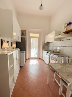 Una cocina con muebles blancos, una mesa de comedor y una estufa.