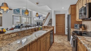 Eine geräumige Küche mit Granit-Arbeitsplatten, Holzschränken und Edelstahlgeräten.