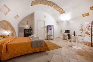 A bedroom with a bed, a desk, a chair, a TV, and artwork on the walls. - GuestHost - Charming room of about 40 square meters, ideal for two people, located on the ground floor of a historic building (there is a small step at the entrance). Furnished with taste and attention to detail, it offers a warm and suggestive atmospher (Bari)