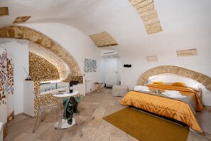 A bedroom with a bed, a small table, and a chair. - GuestHost - Charming room of about 40 square meters, ideal for two people, located on the ground floor of a historic building (there is a small step at the entrance). Furnished with taste and attention to detail, it offers a warm and suggestive atmospher (Bari)