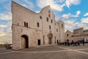 A historic building with a large central archway, multiple smaller arches, and a courtyard.