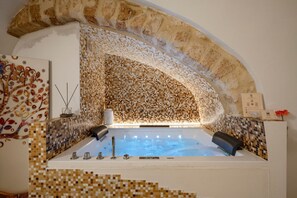 A spa area with a mosaic-tiled wall, a large bathtub, and a decorative wall piece. - GuestHost - Charming room of about 40 square meters, ideal for two people, located on the ground floor of a historic building (there is a small step at the entrance). Furnished with taste and attention to detail, it offers a warm and suggestive atmospher (Bari)