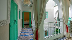 A corridor with green doors, a patterned floor, and a balcony with white railings and green windows. - Riad JABADOR De Marrakech (Marrakech)