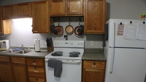 Una cocina con armarios de madera, estufa blanca, refrigerador y microondas.