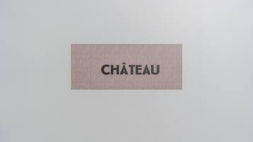 Ein Schild mit dem Wort „CHÂTEAU“ vor rustikalem Hintergrund.