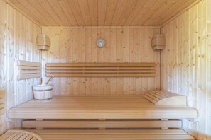 A wooden sauna with benches, a wall-mounted heater, and a clock. - CLOS ST FRANCOIS SPA (Wangenbourg-Engenthal)