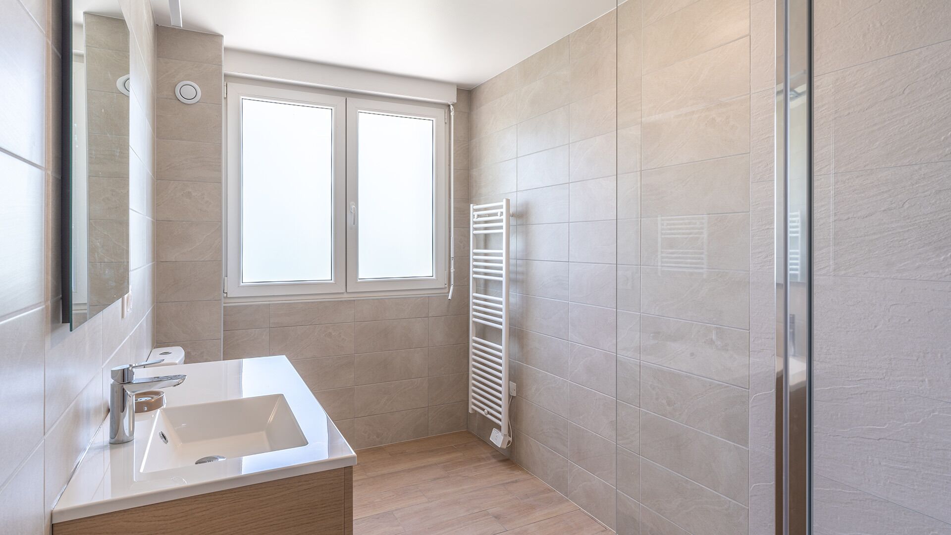 Ein modernes Badezimmer mit großem Fenster, integriertem Waschbecken und Handtuchhalter.
