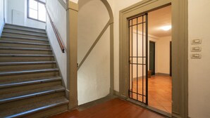 A staircase leading to a room with a tiled floor and a barred door. - Violetta's Home (Firenze)