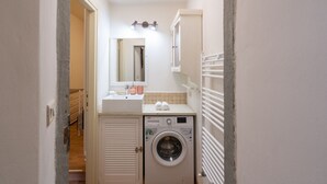 A compact bathroom with a washing machine, a sink, and a mirror. - Violetta's Home (Firenze)