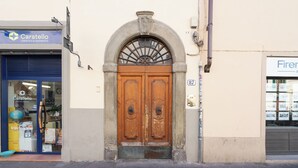 A building with a large wooden double door, a sign for Caratello Logistics & Shipments, and another sign for a place called Firenze. - Violetta's Home (Firenze)