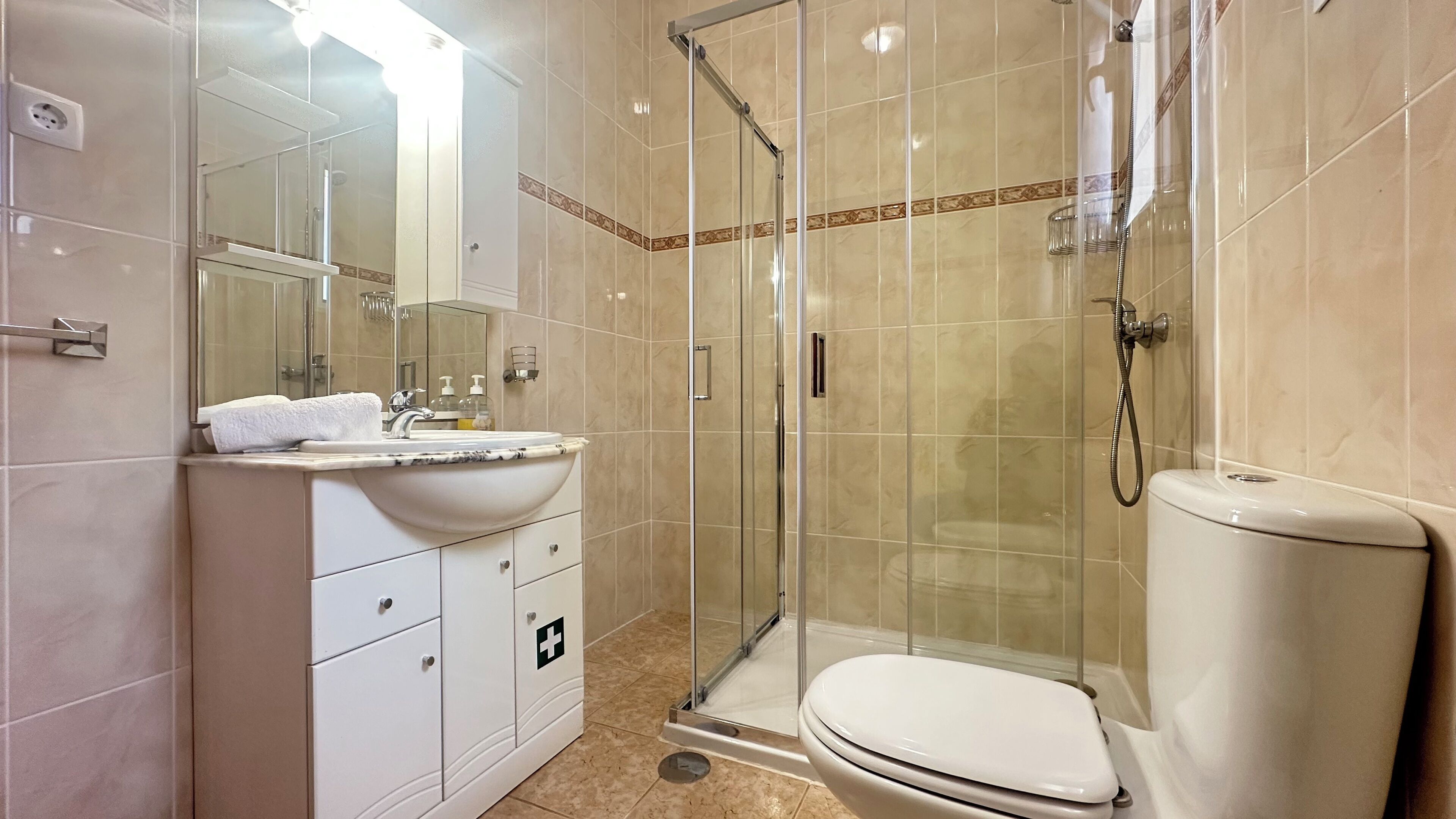 Une salle de bain moderne avec une douche à parois de verre, un lavabo blanc et des toilettes.