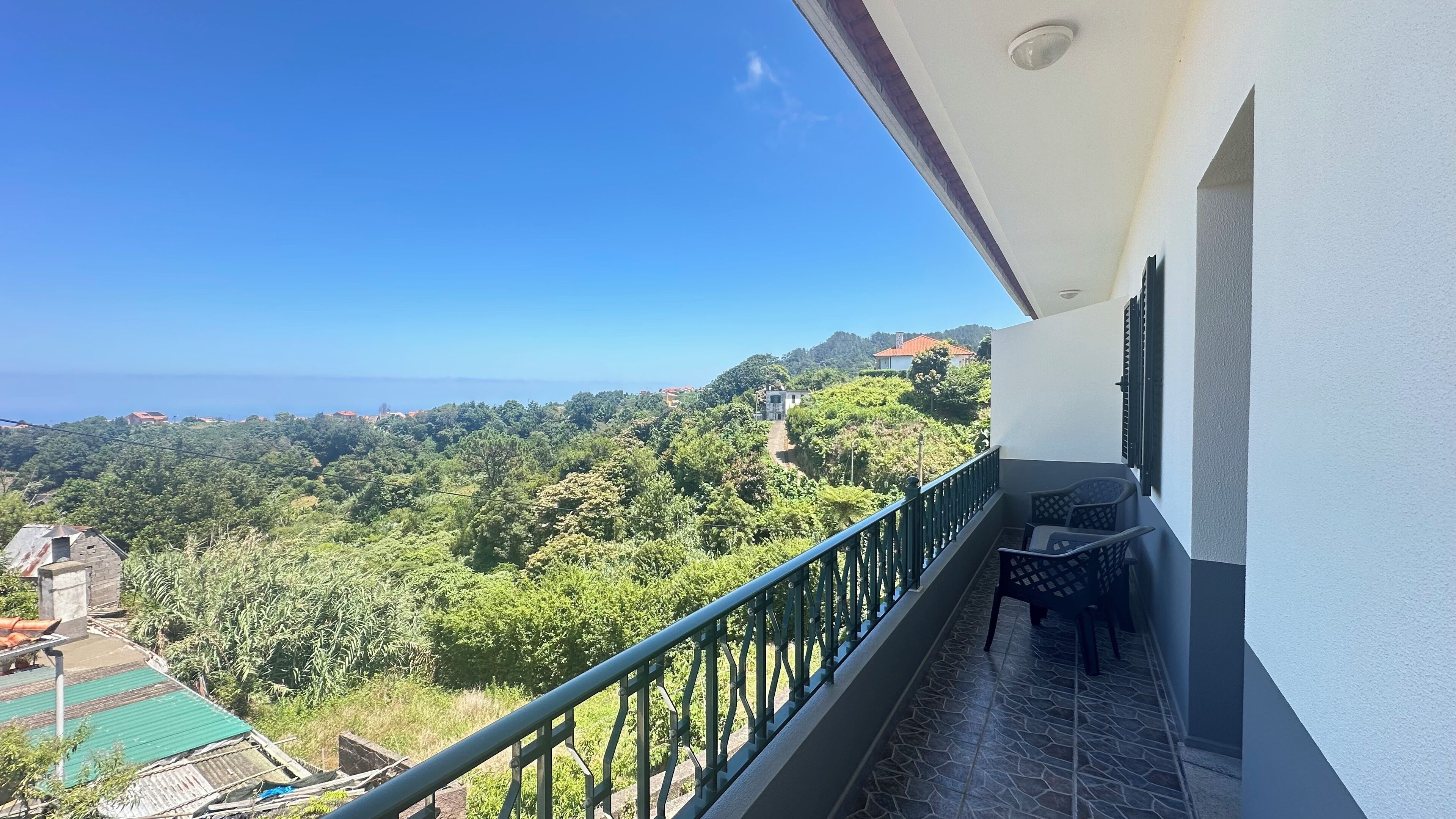 Un balcón con vistas a un paisaje verde exuberante y edificios lejanos.