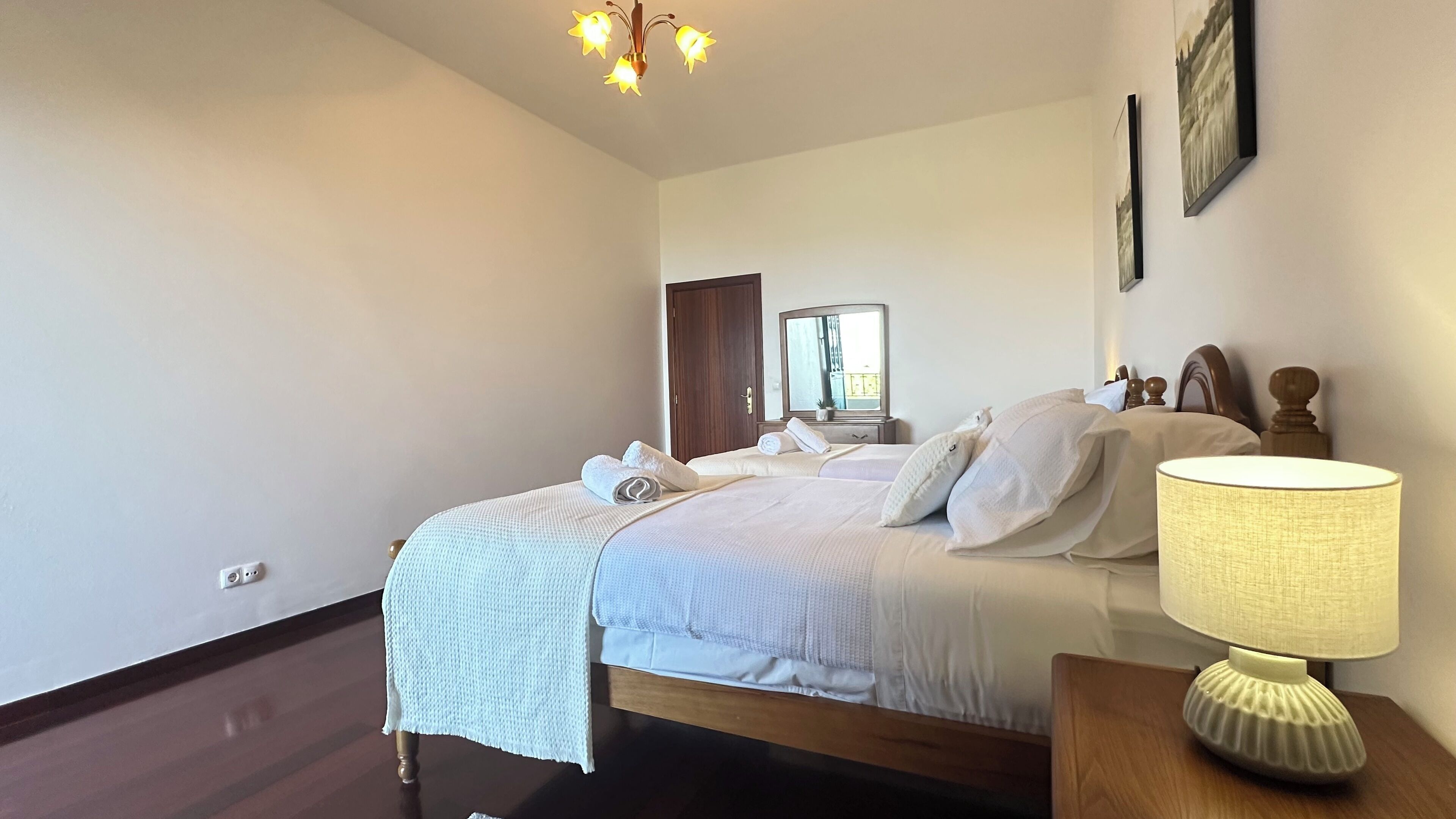 Une chambre à coucher avec un lit, une table de chevet avec une lampe, un miroir et une porte donnant sur une autre pièce.