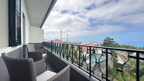 A balcony with wicker furniture and a view of a swimming pool and buildings. - Sea and Sun 4 You - Villa Jardim (Santana)