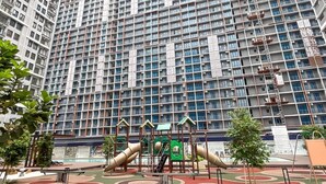 A playground with slides and climbing structures in front of a high-rise building.