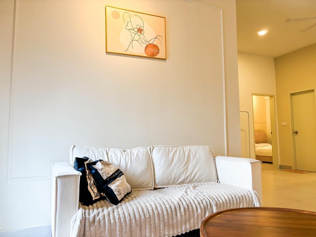 Een witte bank met een gebreid plaid en decoratief kussen, een houten salontafel en een kunstwerk in een lijst aan de muur.