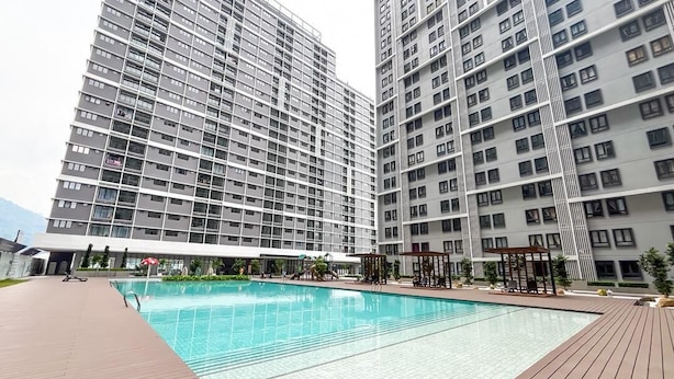 A modern residential building with a swimming pool, high-rise balconies, and a covered outdoor area.