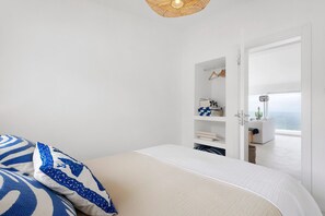 A bedroom with a bed, a wardrobe, and a view of the sea.