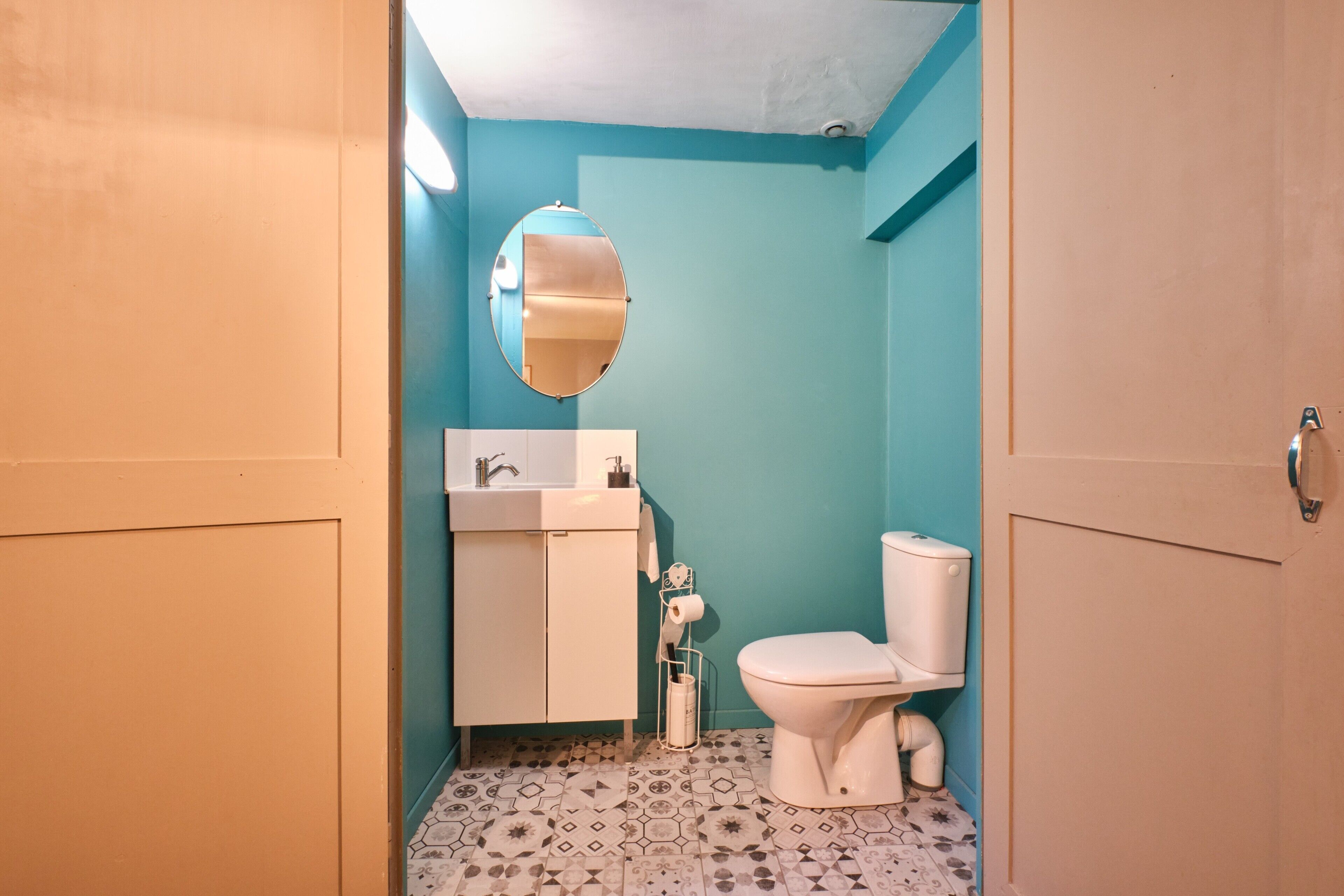A bathroom with a toilet, sink, and mirror.