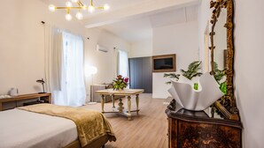 A hotel room with a bed, bedside table, lamp, and a large mirror. - Kepos Rooms & Suites (Palermo)