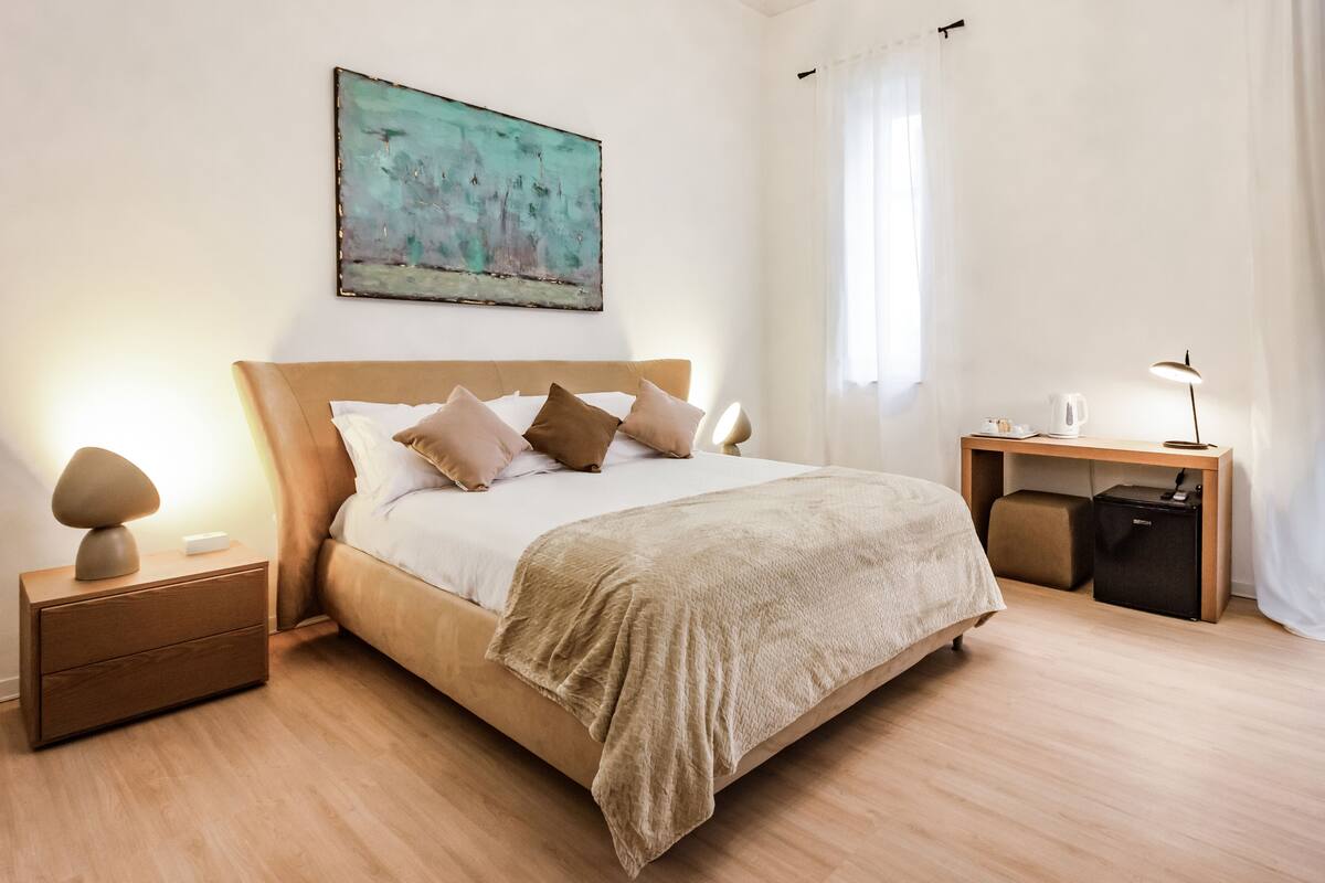 A modern bedroom with a bed, bedside tables, a desk, and a lamp.