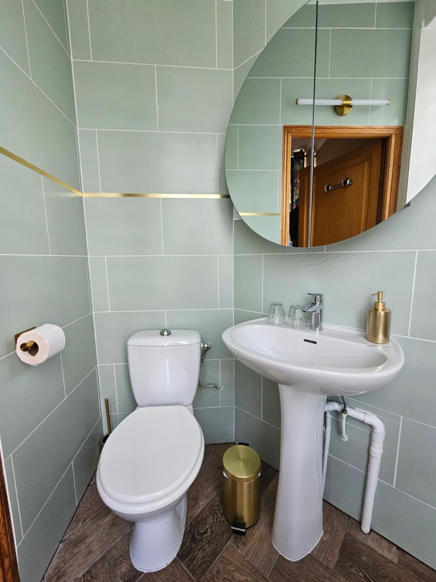 Et badeværelse med toilet, vask og spejl.