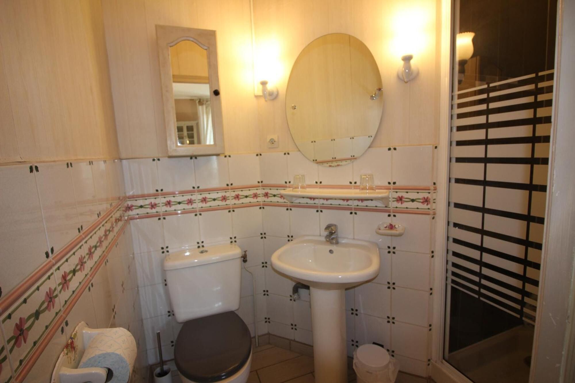 Een badkamer met toilet, wastafel en spiegel.