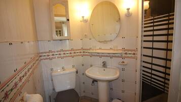 Een badkamer met toilet, wastafel en spiegel.