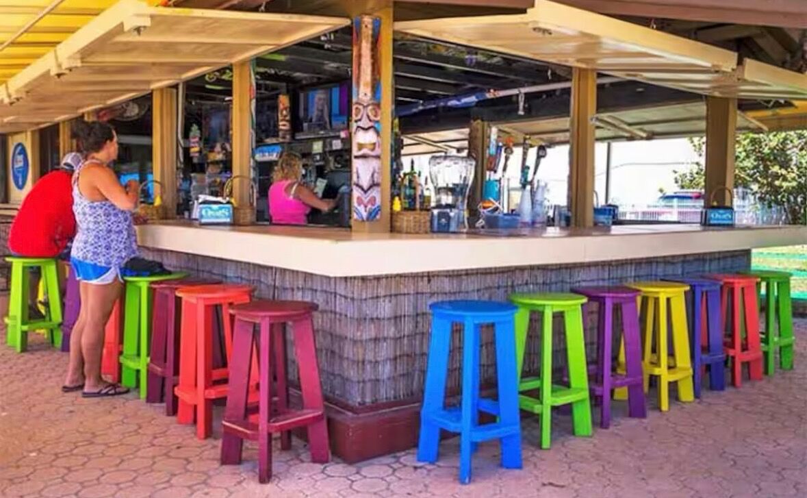 Una zona de bar con taburetes de colores y una barra.