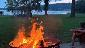 A fire pit with animal silhouettes, a wooden bench, and a lake view.