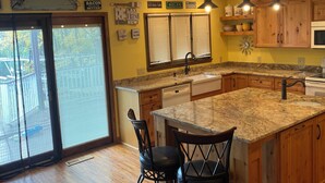 A kitchen with wooden cabinets, a granite countertop, and a large island with bar stools.