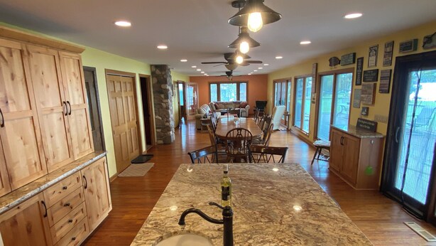 A spacious kitchen with a granite countertop, wooden cabinets, and a central island with a sink.