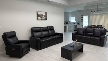 Un salon moderne avec un canapé en cuir noir, une table basse noire et un fauteuil inclinable.