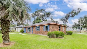 A single-story brick house with a front porch, surrounded by a well-maintained lawn and a palm tree. - House of Smurf, Close to Savannah State (Savannah)