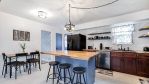 A modern kitchen with a central island, bar stools, and a dining area with a table and chairs. - House of Smurf, Close to Savannah State (Savannah)
