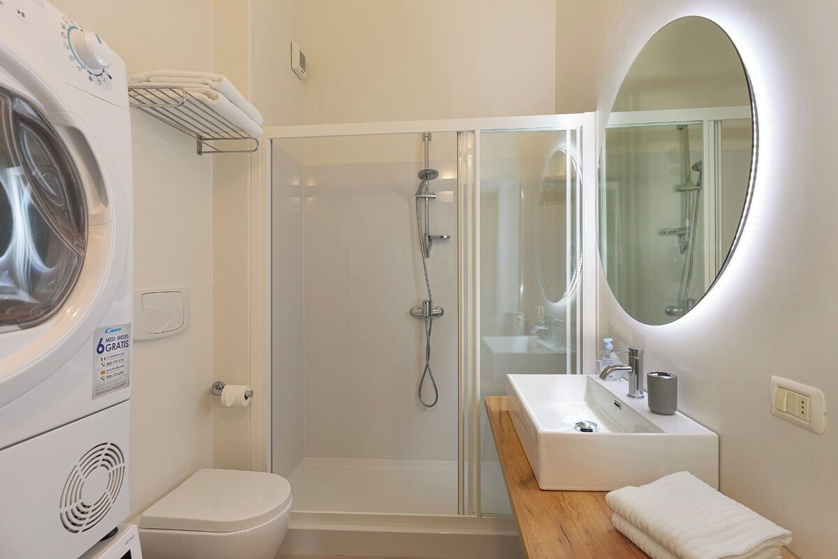 A modern bathroom with a glass-enclosed shower, a built-in sink, and a washing machine.