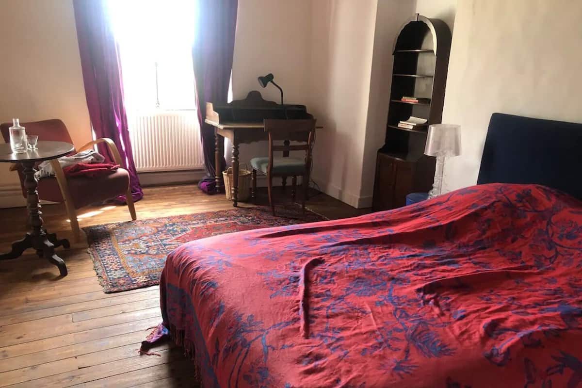A room with a bed, a desk, a chair, a bookshelf, and a radiator.