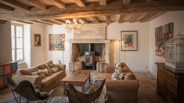 A cozy living room with exposed wooden beams, a fireplace, and modern furniture.