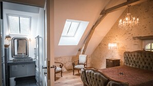 A bedroom with a large bed, a chandelier, and a skylight.