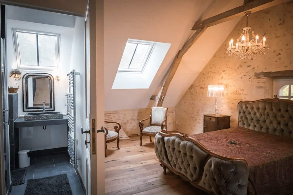 A bedroom with a large bed, a chandelier, and a skylight.