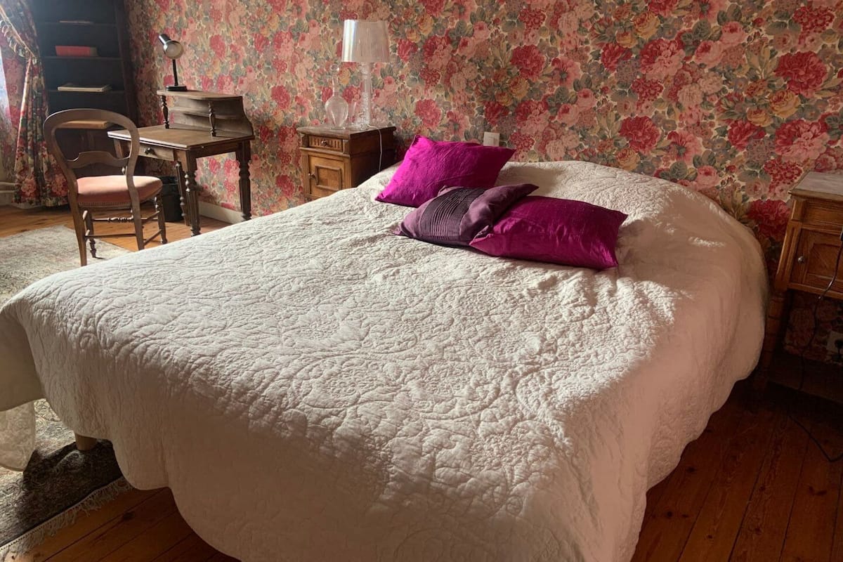 A bedroom with a large bed, a desk, and a chair.