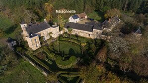 A large, historic estate with multiple buildings, extensive gardens, and a moat.