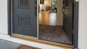 A dark wooden door with decorative panels and a welcome mat. - Charming vacation rental steps away from River Island Golf Course (Porterville)